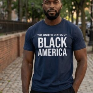 A man wearing a navy blue heavyweight cotton t-shirt with "THE UNITED STATES OF BLACK AMERICA" printed across the chest in bold, white uppercase typography.